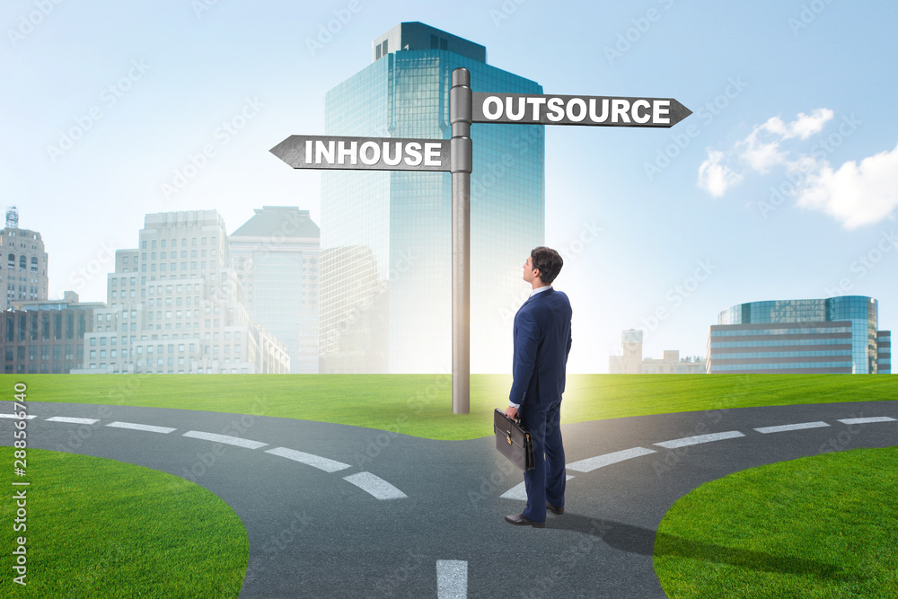 Businessman at crossroads deciding between outsourcing and inhou Businessman at crossroads deciding between outsourcing and inhou