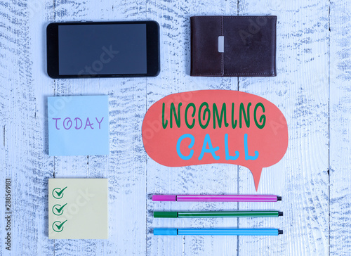 Word writing text Incoming Call. Business photo showcasing Inbound Received Caller ID Telephone Voicemail Vidcall Smartphone pens blank speech bubble sticky notes wallet wooden background photo