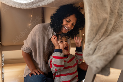 Mother and her little daughter playing in a blanket fort