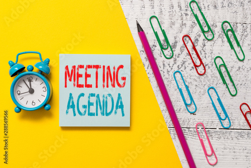 Handwriting text Meeting Agenda. Conceptual photo items that participants hope to accomplish at a meeting Notepad marker pen colored paper sheet clips alarm clock wooden background