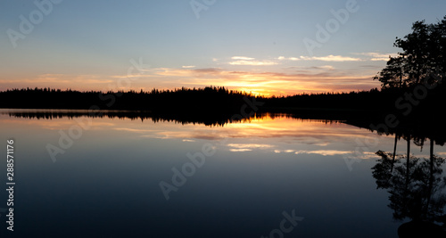 sunset clouds are reflected in the calm mirror water of the lake