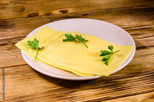 Sliced cheese and parsley in ceramic plate on wooden table