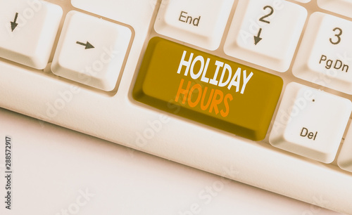 Text sign showing Holiday Hours. Business photo showcasing employee receives twice their normal pay for all hours White pc keyboard with empty note paper above white background key copy space photo