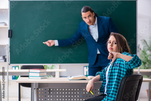 Young handsome teacher and female student in the classroom