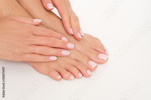 Female hands on feet isolated on white background.
