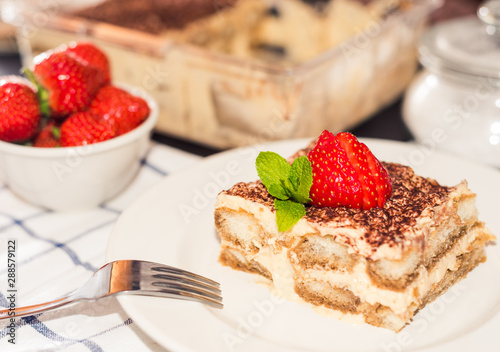 gourmet tiramisu dessert with strawberries in a beautiful plate on a dark background