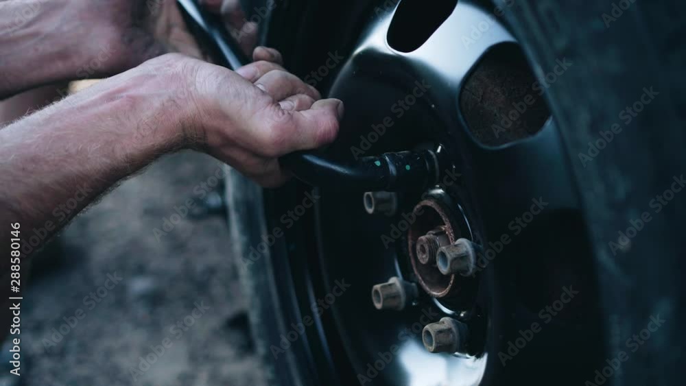 The man tightens the nuts on the wheel after replacement. Breakage EN