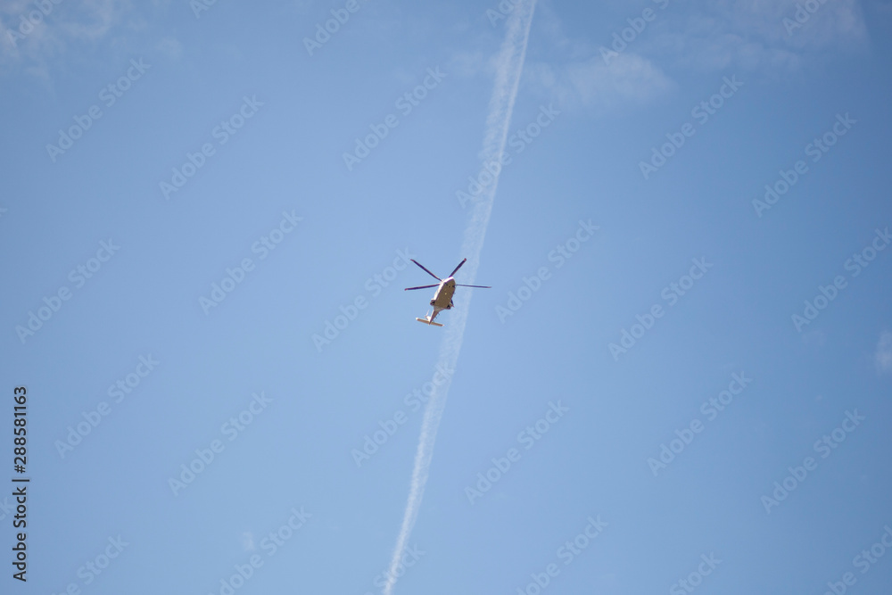 A helicopter flies in the sky. Propeller transport on a background of blue sky. Bottom view of the movement of the aircraft. A helicopter flies in the sky. Propeller transport on a background of blue sky. Bottom view of the movement of the aircraft.