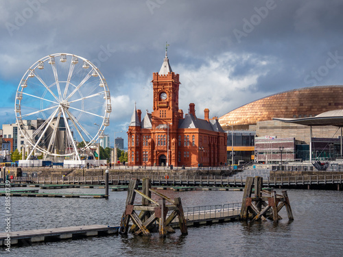 Cardiff Bay,  Cardiff, Wales. Late afternoon in Cardiff Bay with a dark sky over the old Pierhead building and the sun glinting on the Millennium Centre roof.  The old staithes still prominent. photo