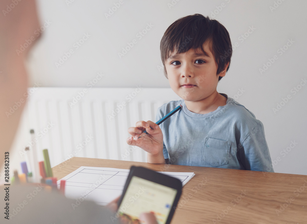 Preschool kid holding pencil with blurry foreground of a man typing on mobile phone, Selective focus of Child doing homework with blurry foreground of father searching internet on smart phone. Preschool kid holding pencil with blurry foreground of a man typing on mobile phone, Selective focus of Child doing homework with blurry foreground of father searching internet on smart phone.