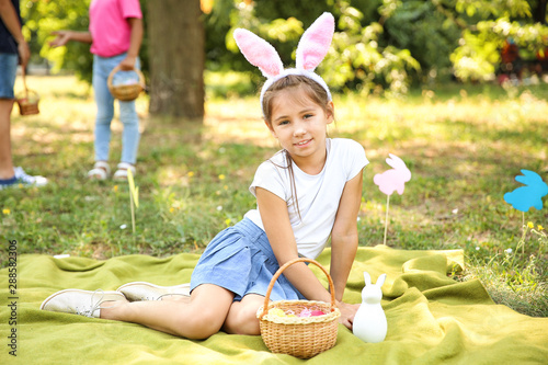 Little girl with bunny ears and Easter eggs in park