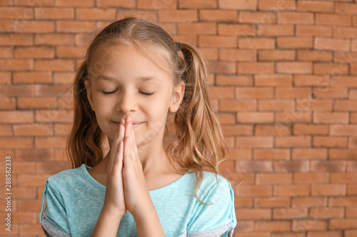 Cute little girl praying ag...