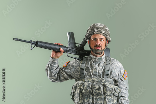 Soldier with assault rifle on color background