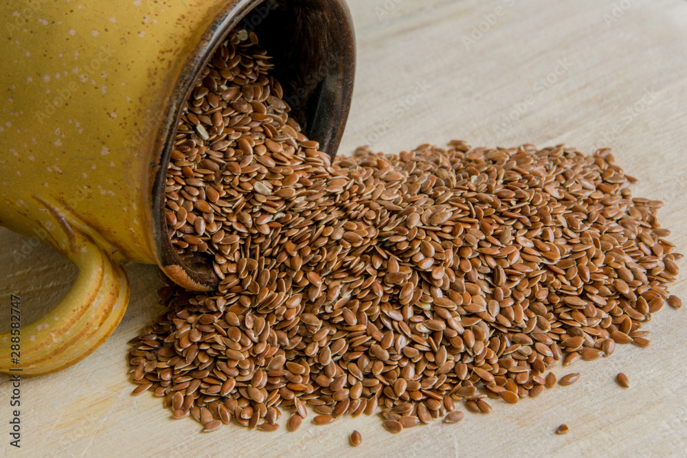 Obraz premium Flax seeds in a cup on wooden background