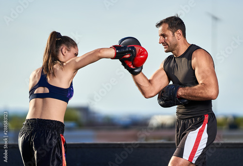 Young woman boxer hitting pads outdoor