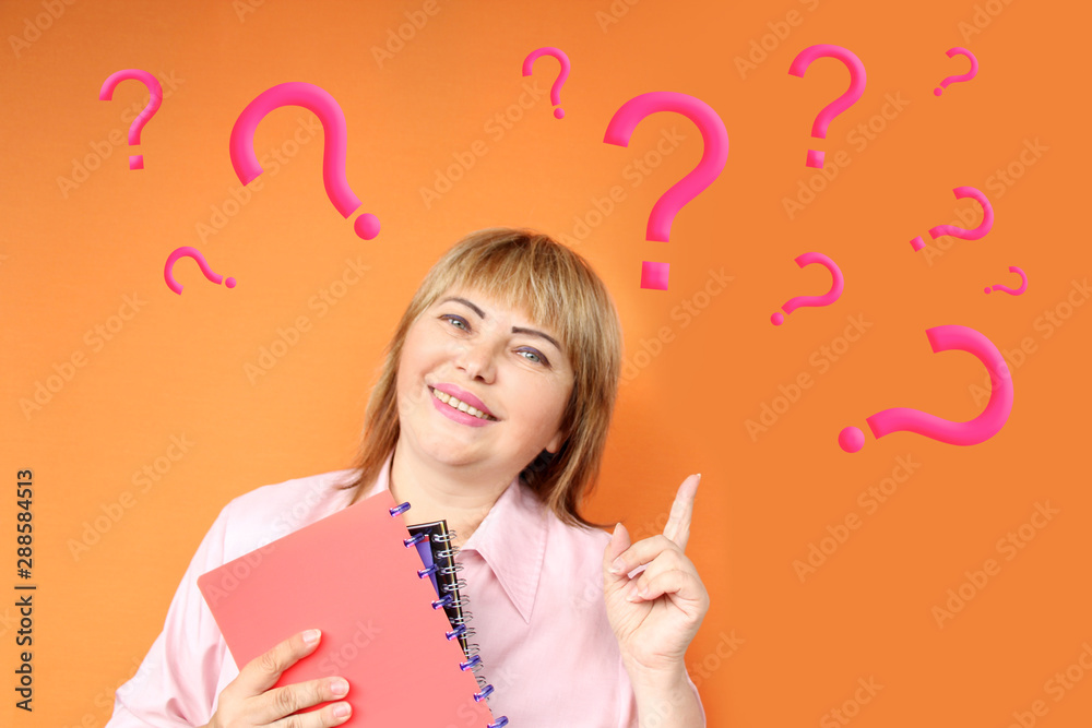 European woman with notebooks in hand smiles and shows fingers on the background of a lot of white question marks on a chalkboard for chalk, text, concept close-up, copy space European woman with notebooks in hand smiles and shows fingers on the background of a lot of white question marks on a chalkboard for chalk, text, concept close-up, copy space