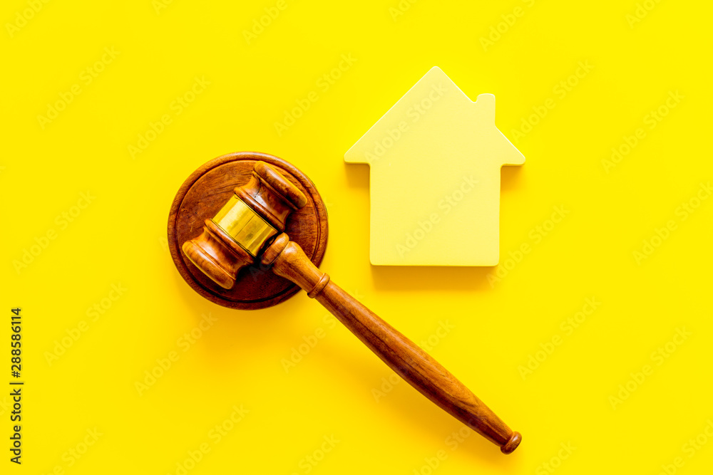 Inscribed gavel, house figure for inheritance concept on yellow background top view