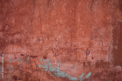 Red plaster wall with pealing paint