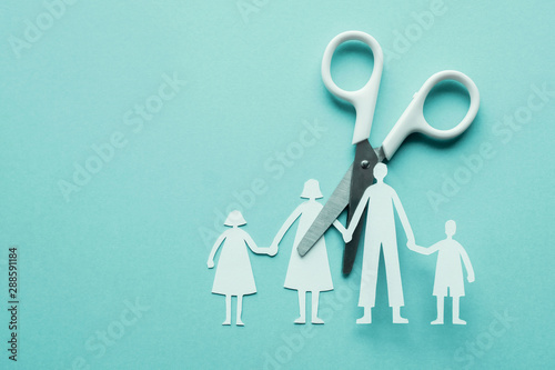 White scissor cutting family paper cut out on blue background, causes and effects on child development and behavior of dysfunctional family, divorce broken home , social distancingconcept