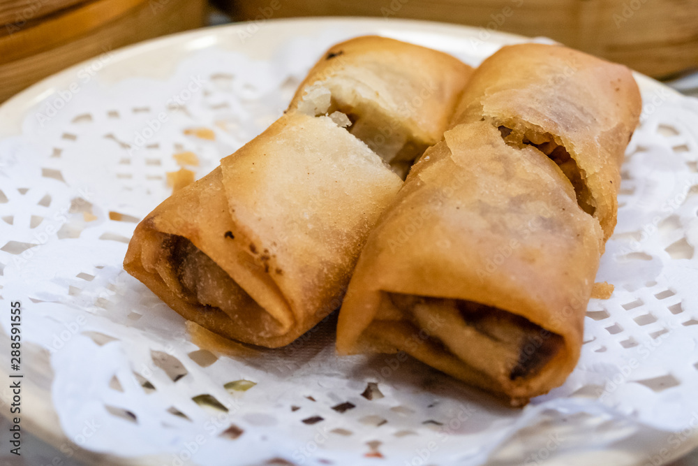 Spring rolls in a plate in front of bamboo steamers Spring rolls in a plate in front of bamboo steamers