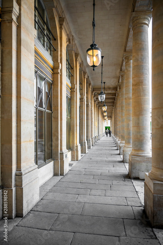 Man and woman walk through portico with columns