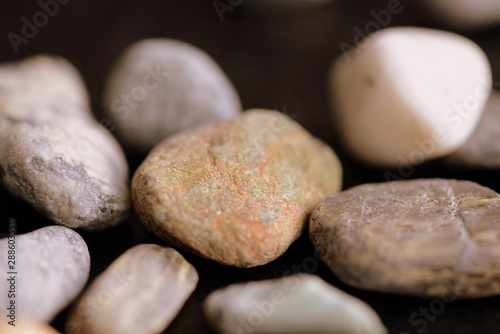 Scattered pebble stones on a dark background close up