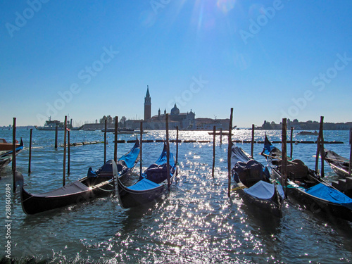 Gondolas near Saint Mark square, Venice, Italy. Scenic view on Venetian landmarks - water surface and seafront with famous traditional Italian boats.