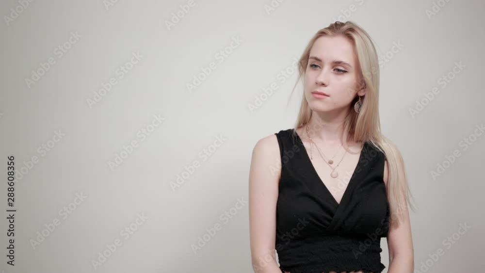 blonde girl in a black dress over isolated white background shows emotions blonde girl in a black dress over isolated white background shows emotions