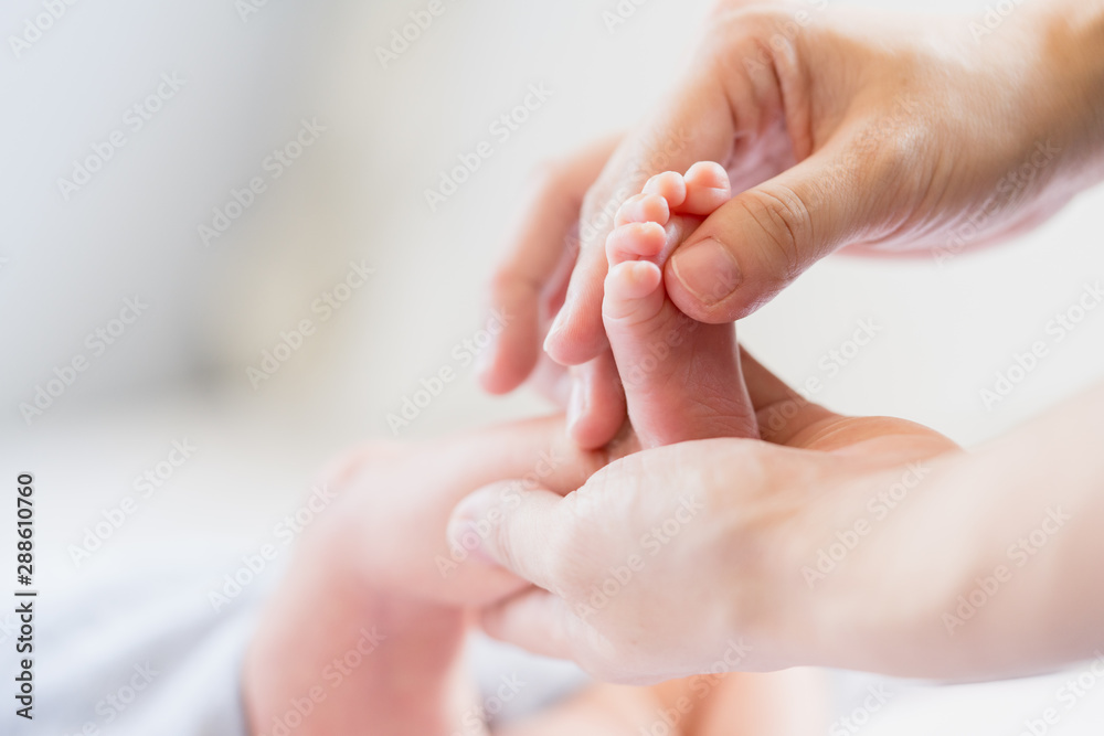 Close up scene of baby massage therapy for baby happy and reduce crying with sleep more, apply baby oil on the foot, selective focused on baby foot and shot on soft natural sunlight with copy space.