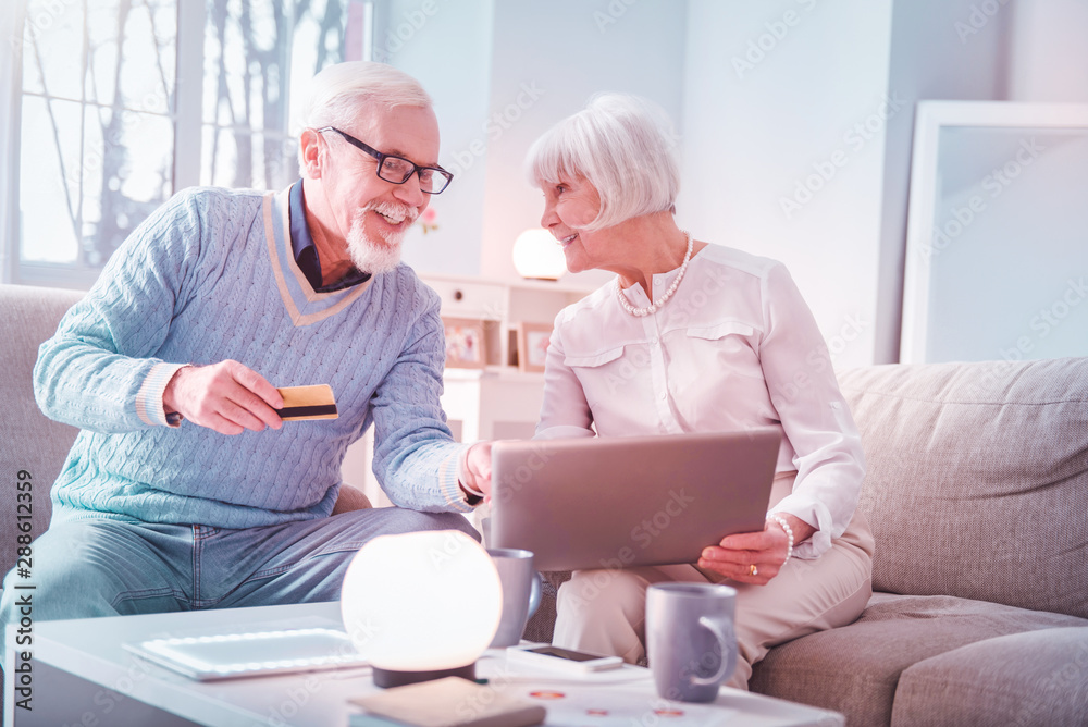 Modern elderly man and woman processing payment while paying online