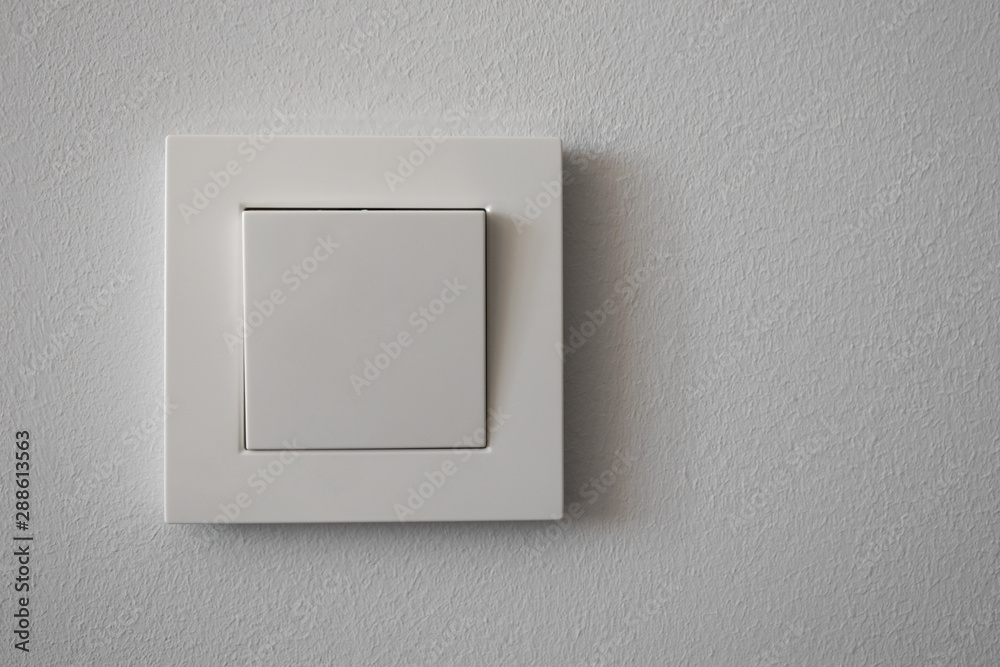 White plastic light switch on light gray wall, close-up. Copy space. White plastic light switch on light gray wall, close-up. Copy space.