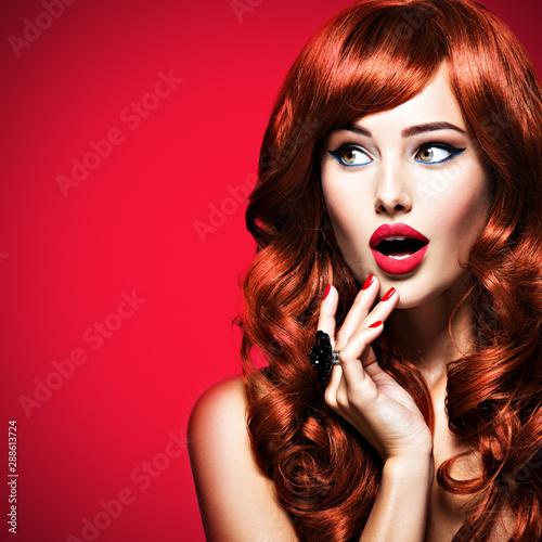Beautiful surprised young woman very amazing looks away. Red hairstyle