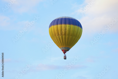Gas hot air balloon in a yellow and blue colour on a cloudy blue sky