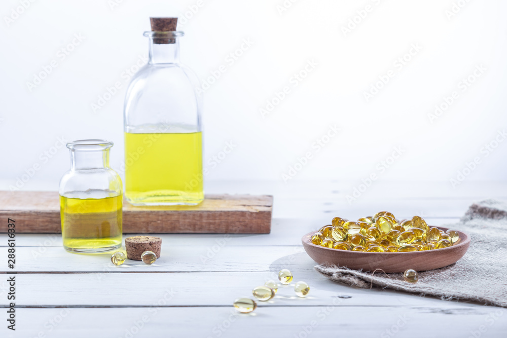 Evening primrose oil in capsules and in bottles, on a white wooden base. Health care concept.
