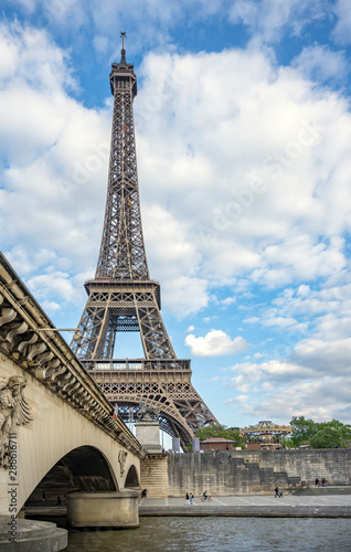 View of the Eiffel Tower over the stone arch bridge