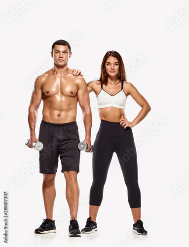 Portrait of strong healthy man and woman posing with dumbbells