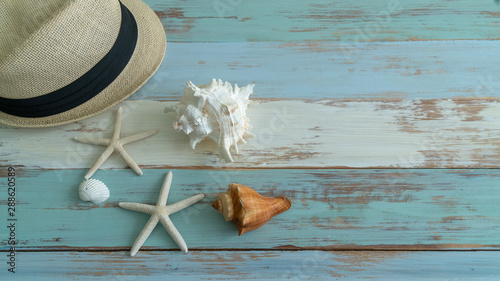The composition of hats, shells, glasses and shoes placed on wooden floors to create a beach background.