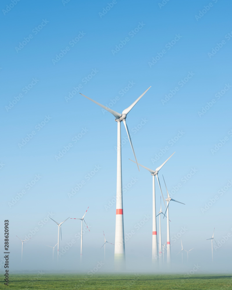 wind turbines in green meadow near aurich in ostfriesland on misty morning in august - obrazy, fototapety, plakaty 