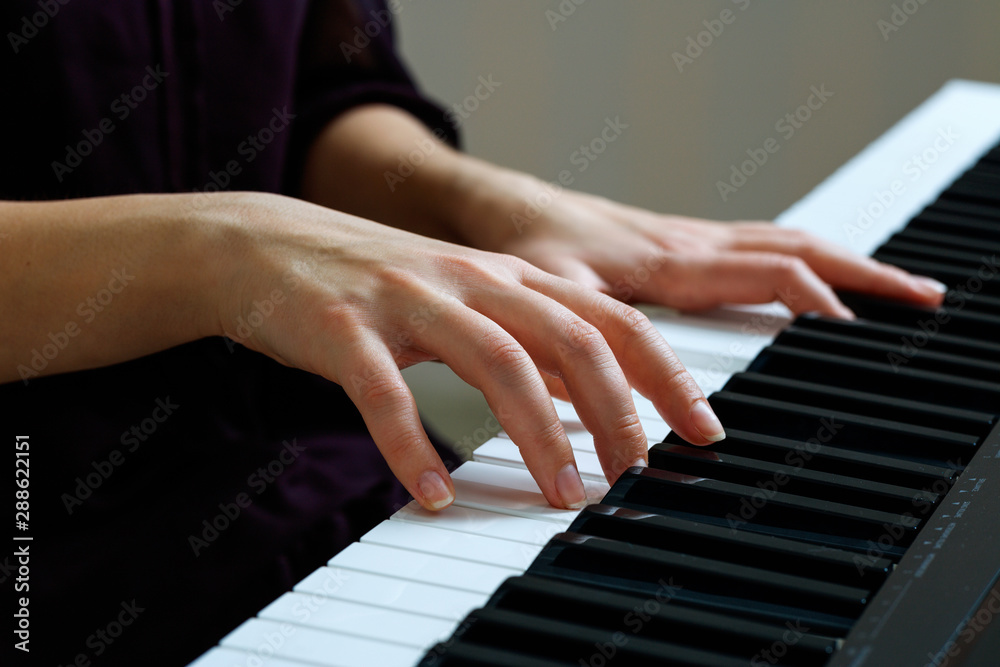 Fototapeta premium Young woman playing piano