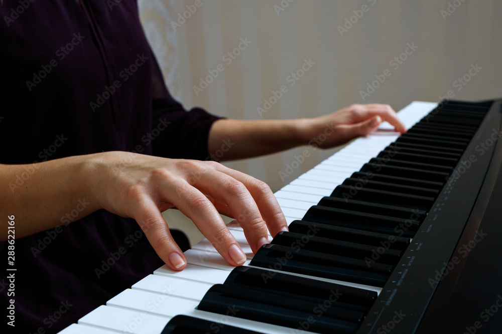 Fototapeta premium Young woman playing piano