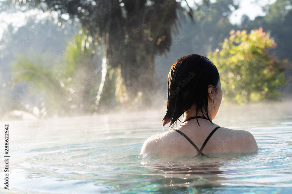 Fototapeta premium A young woman relaxing in an infinity pool