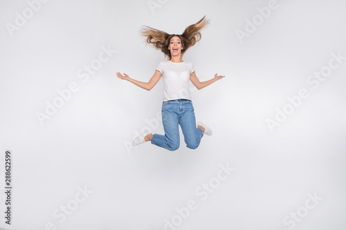 Full length body size photo of crazy funny cute nice attractive girl jumping high wearing jeans denim happy while isolated with white background