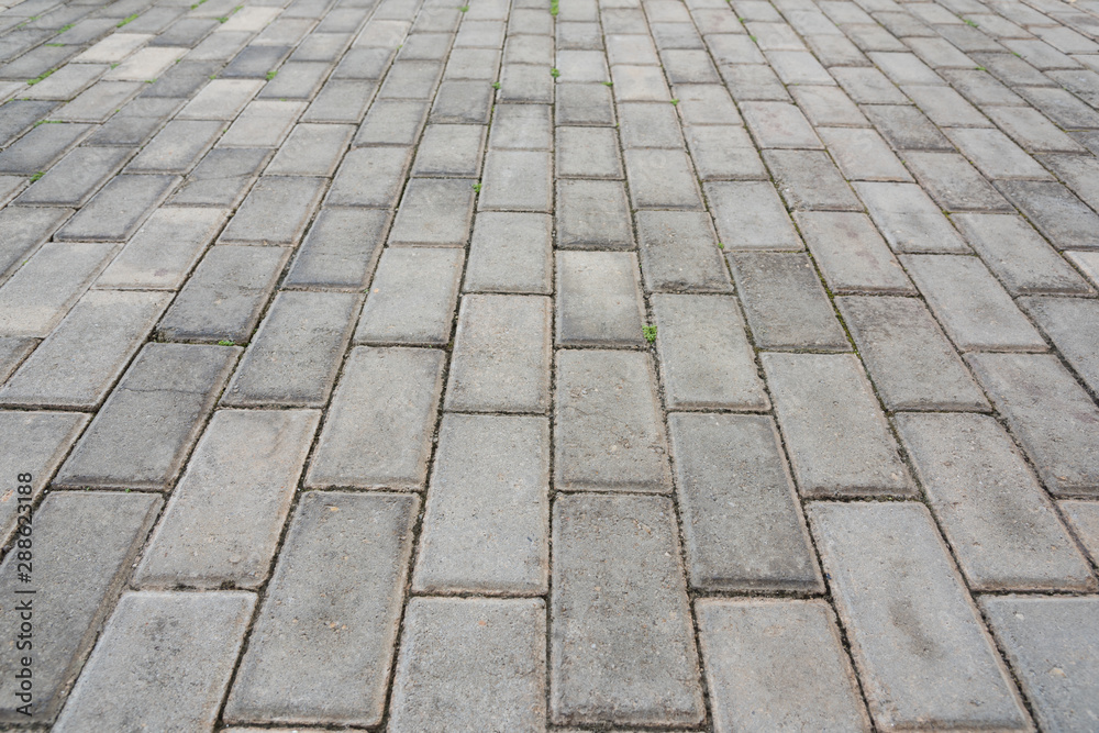 Low angle closeup of old pedestrian pavement surface paved with gray stone bricks