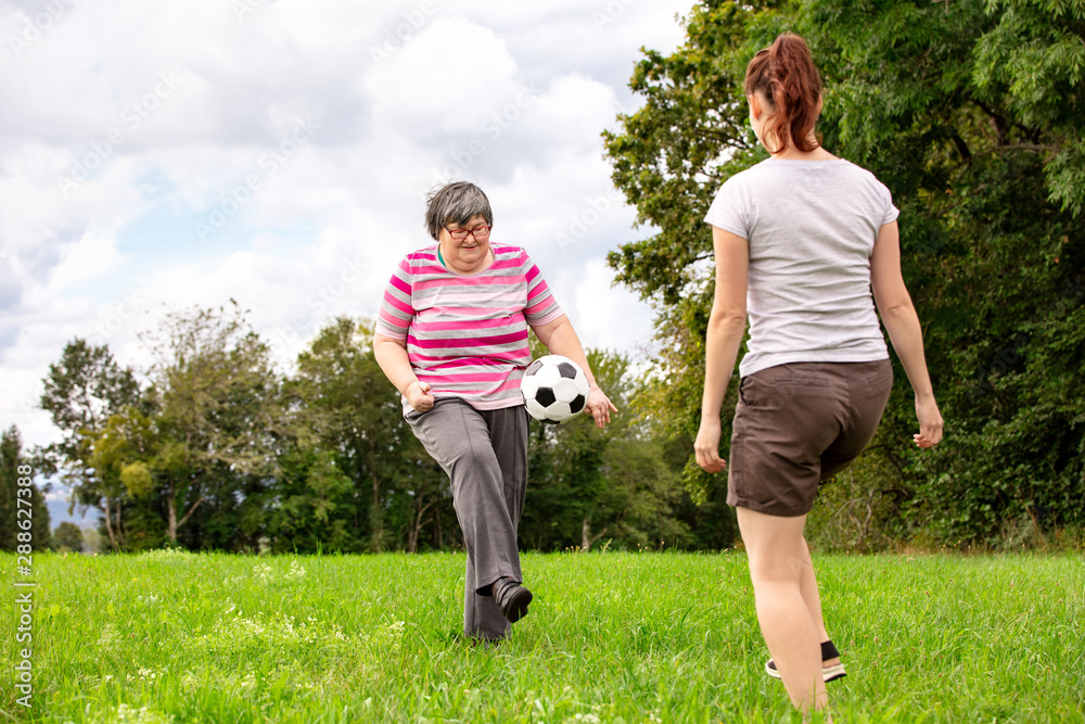 Geistig behinderte Frau spielt Fussball mit einer Pflegerin spielen gemeinsam Ball
