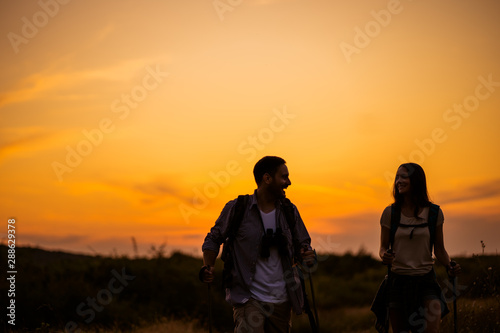 Happy couple is hiking in mountain in sunset.