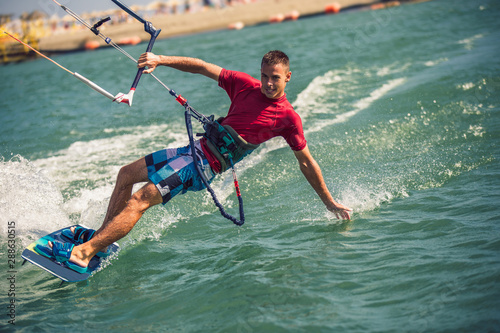 Professional kiter makes the difficult trick on a beautiful background. Kitesurfing Kiteboarding action photos man among waves quickly goes