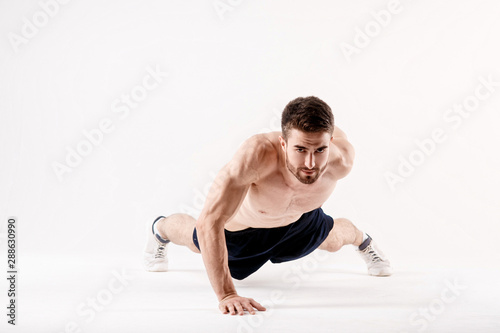 young man with a beard of a sports physique doing push-ups from the floor on a white isolated background, sportsman goes in for sports © Ilnur
