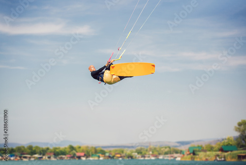 Professional kiter makes the difficult trick on a beautiful background. Kitesurfing Kiteboarding action photos man among waves quickly goes
