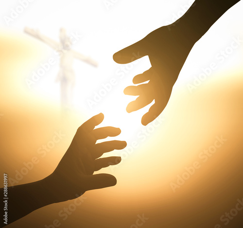 Photography Silhouette of hands reaching out to each other with Jesus on the cross in a brig