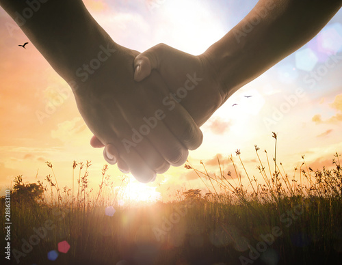 Corporate social responsibility (CSR) concept: Two human shaking hands after good deal on autumn sunset background